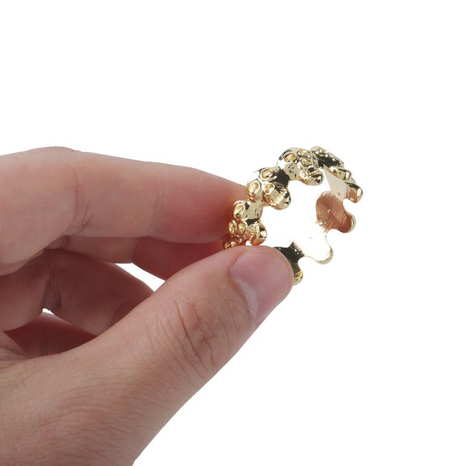 Banoch eikelring doodskop goud cockring geklemd tussen 2 vingers